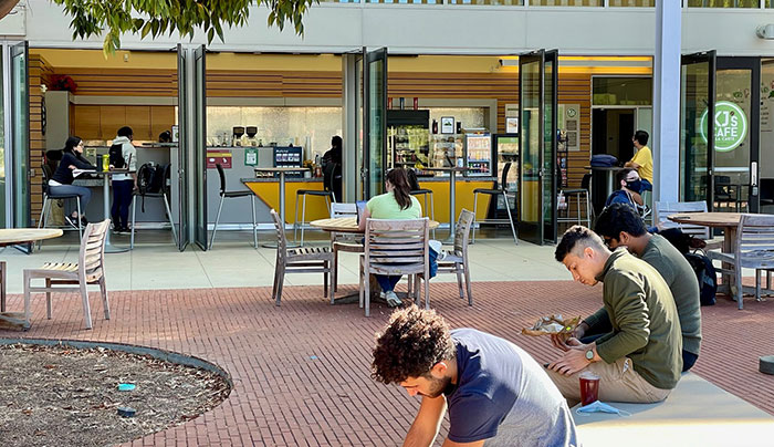 Students sitting outside and inside a cafe area
