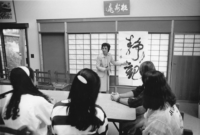 Woman teaching calligraphy to three students
