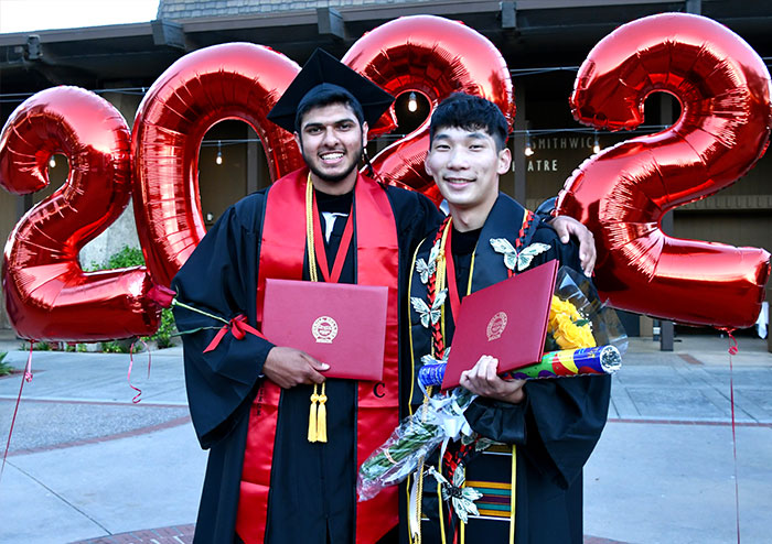 two male graduates holding diplomas