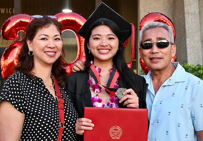 Female graduate holding medal next to parents