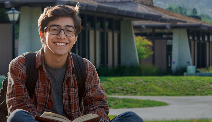 Young male student siting in front of campus building